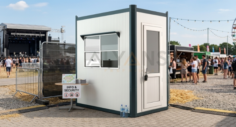 Bir lunaparkın girişinde bilet gişesi olarak konumlandırılmış, geniş pencereli, beyaz sandviç panel duvarlı ve antrasit gri detaylara sahip modern Alyans Prefabrik panel kabin.