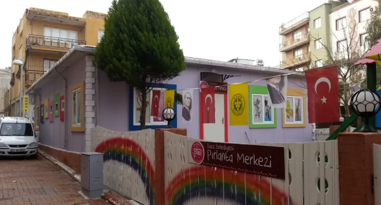 Renkli pencereli ve grafik giydirmeli prefabrik anaokulu binası ana giriş ve çevre güvenlik çiti detayı